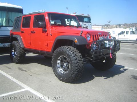1968 Ford Mustang - A bright red Jeep Wrangler is parked in a lot, equipped with off-road tires and a winch.