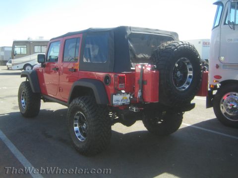 1968 Ford Mustang - This red Jeep Wrangler is equipped with a soft top and a rear-mounted spare tire and gas cans.