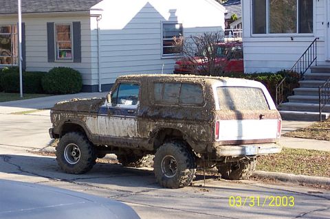 1978 Ford Bronco - This heavily mud-caked 1978 Ford Bronco is parked on a residential street.