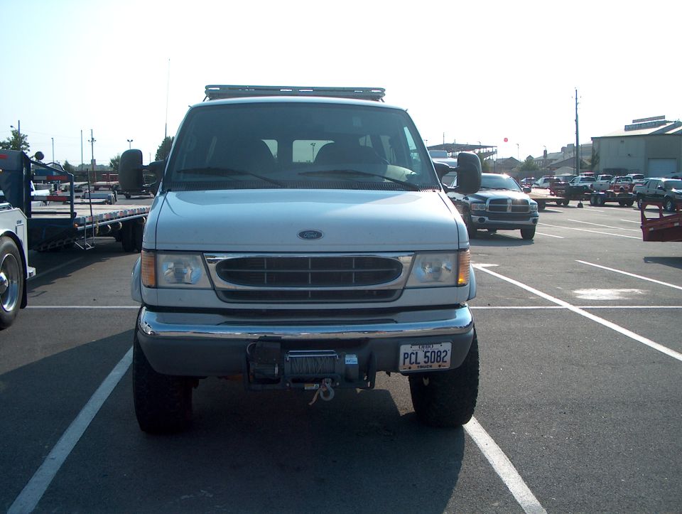 Front view of a silver lifted Ford Econoline 4x4 van with bumper-mounted winch
