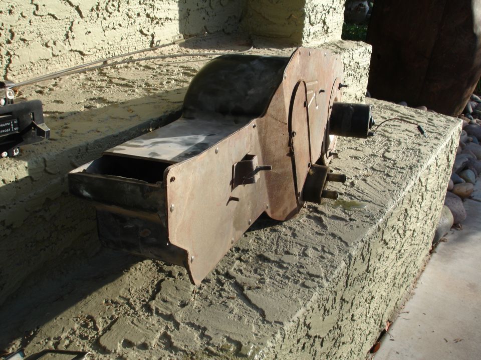 Rusty metal heater box or blower housing sitting on a stucco wall