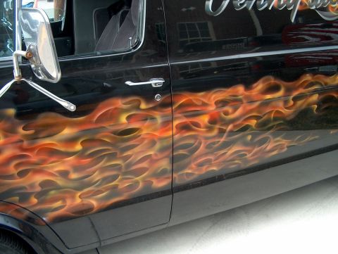 1978 Ford Bronco - A black van displays custom flame graphics on its side door.