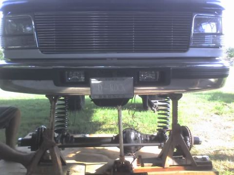 1995 Ford Bronco - Front view of a 1995 Ford Bronco undergoing suspension maintenance, with its front end elevated on jack stands.