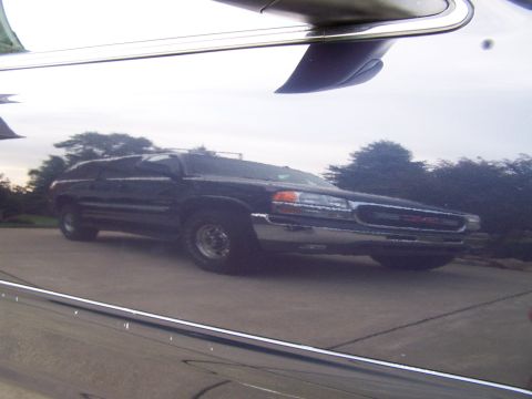 2003 Ford Crown Victoria - Reflection of a black GMC SUV shows its front grille and headlights. The vehicle appears to be from the early 2000s.