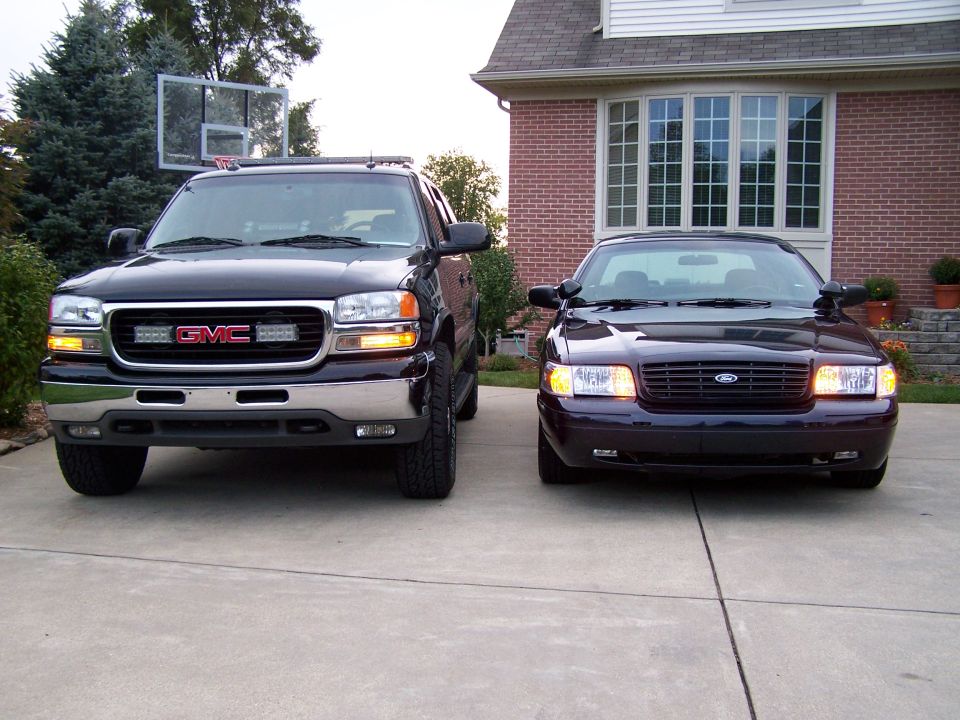 Front view of a GMC pickup and a Ford Crown Victoria parked in a driveway