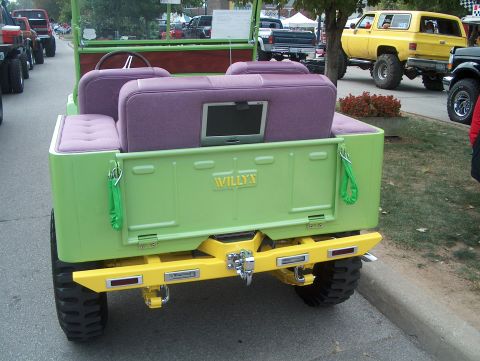 1978 Ford Bronco - This custom Jeep features a bright green exterior, purple upholstered seats, and a prominent yellow rear bumper with 'WILLYS' badging.