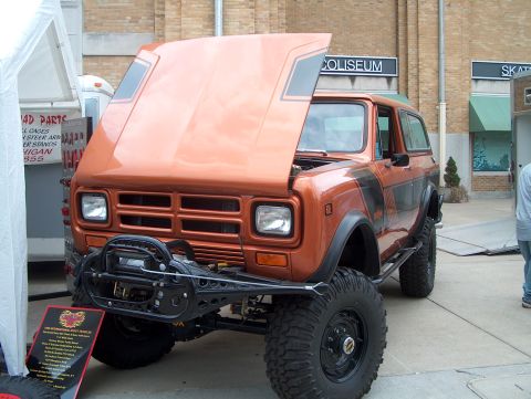 1978 Ford Bronco - Orange International Scout II with hood open and winch bumper on display.