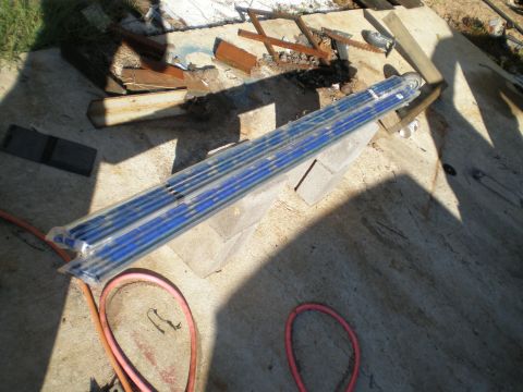 1966 Ford Mustang - Unidentified blue fluorescent light tubes are stored outdoors on concrete blocks, with construction debris in the background.