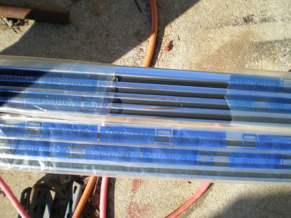 Several chrome trim pieces wrapped in plastic with blue 'MOTOWELL' tape