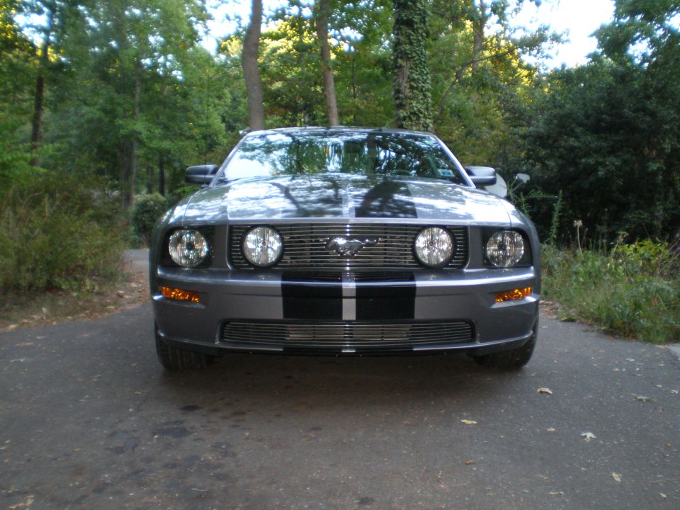 Gray Ford Mustang with black racing stripes, front view, parked on asphalt driveway