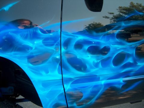 1978 Ford Bronco - A vehicle side is painted with vibrant blue flames, with a reflection of a person visible in the upper portion.