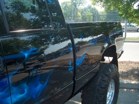 1978 Ford Bronco - A black pickup truck is shown from the side, custom blue flame graphics and a lifted suspension.