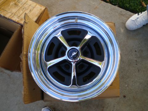 1966 Ford Mustang - A close-up of a chrome wheel, likely from a 1966 Ford Mustang, rests on cardboard boxes.