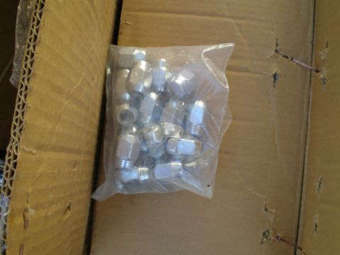 1966 Ford Mustang - A clear plastic bag contains multiple metal lug nuts, sitting within a corrugated cardboard box.