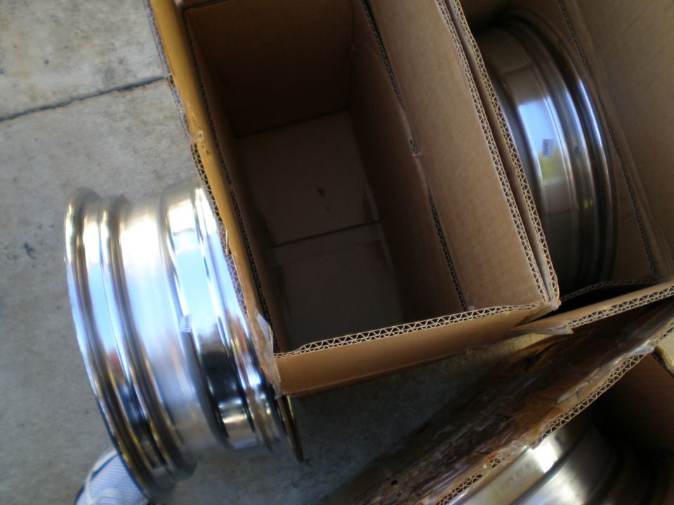 Two chrome car wheels in cardboard boxes, one partially visible