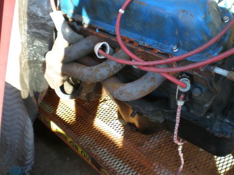1966 Ford Mustang - Close-up of an engine with blue valve covers and rusty exhaust manifolds.