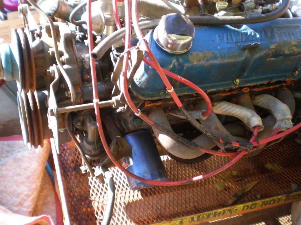 Blue engine with red spark plug wires and exhaust manifolds. Text 'POWERED' is visible on the valve cover