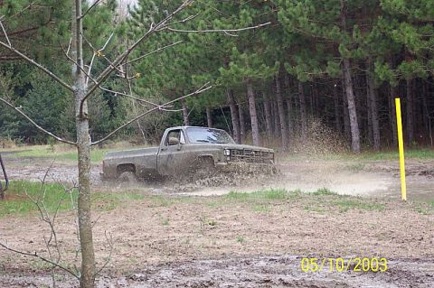 1978 Ford Bronco - Pickup truck navigating a muddy off-road course, kicking up water and dirt.