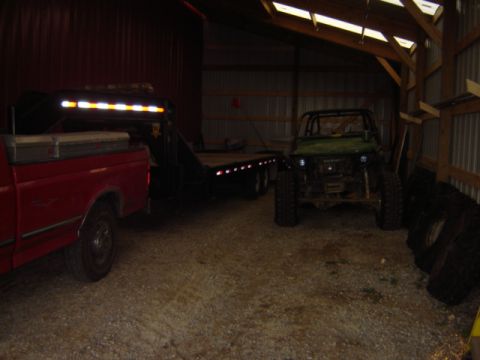 1992 Ford Bronco - A red truck and trailer are parked next to a green off-road vehicle in a barn.