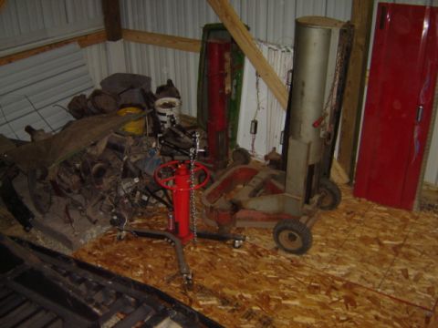 1992 Ford Bronco - A cluttered shop scene with engine parts and various equipment, including a floor jack and a tall tank.