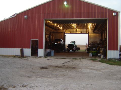 1992 Ford Bronco - Several vehicles are parked inside a large red barn with the bay doors open.