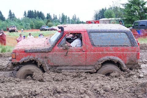 1989 Ford Bronco - A red 1989 Ford Bronco navigates a mud bog during an event.