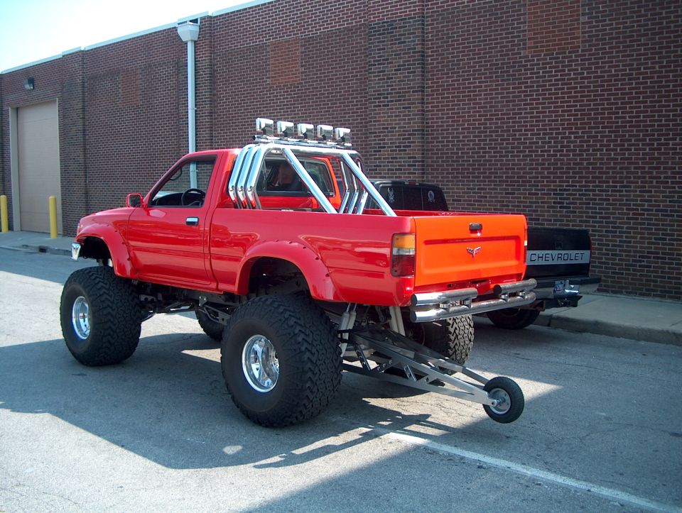 Red lifted pickup truck with roll bar, exhaust stacks, and trailer hitch