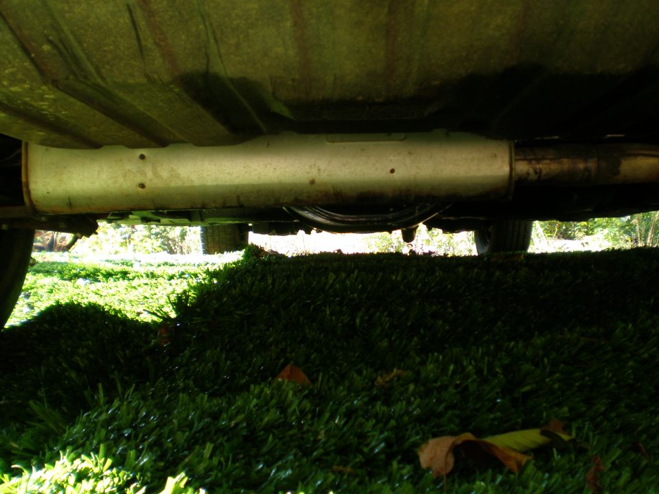 Underside of a car showing the exhaust system and part of a tire