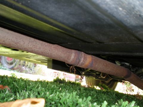 1966 Ford Mustang - Underside view of a vehicle's rusty exhaust pipe, with grass visible below.