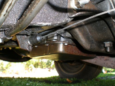 1966 Ford Mustang - A low-angle view of the undercarriage of a vehicle, revealing mechanical components and a tire.