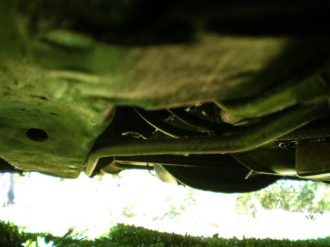 1966 Ford Mustang - A low-angle shot reveals the underside of a vehicle, focusing on suspension components and exhaust piping.