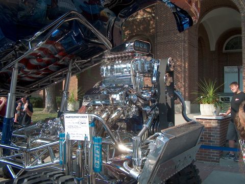 1978 Ford Bronco - A highly customized monster truck is displayed outdoors, a prominent, polished engine and patriotic graphics.