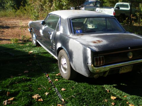 1966 Ford Mustang - This 1966 Ford Mustang coupe is shown in a rear three-quarter view, with a primer finish and some rust spots visible.