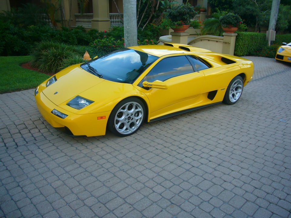 Yellow Lamborghini Diablo coupe, 3q-front view, on brick driveway