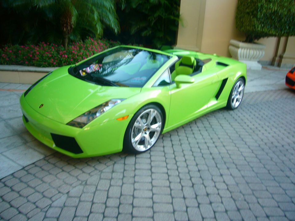 Lime green convertible sports car, front 3/4 view, parked on cobblestone driveway