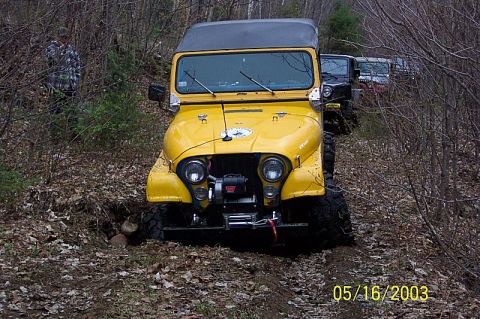 1978 Ford Bronco - A line of off-road vehicles, led by a yellow Jeep, navigates a wooded trail.