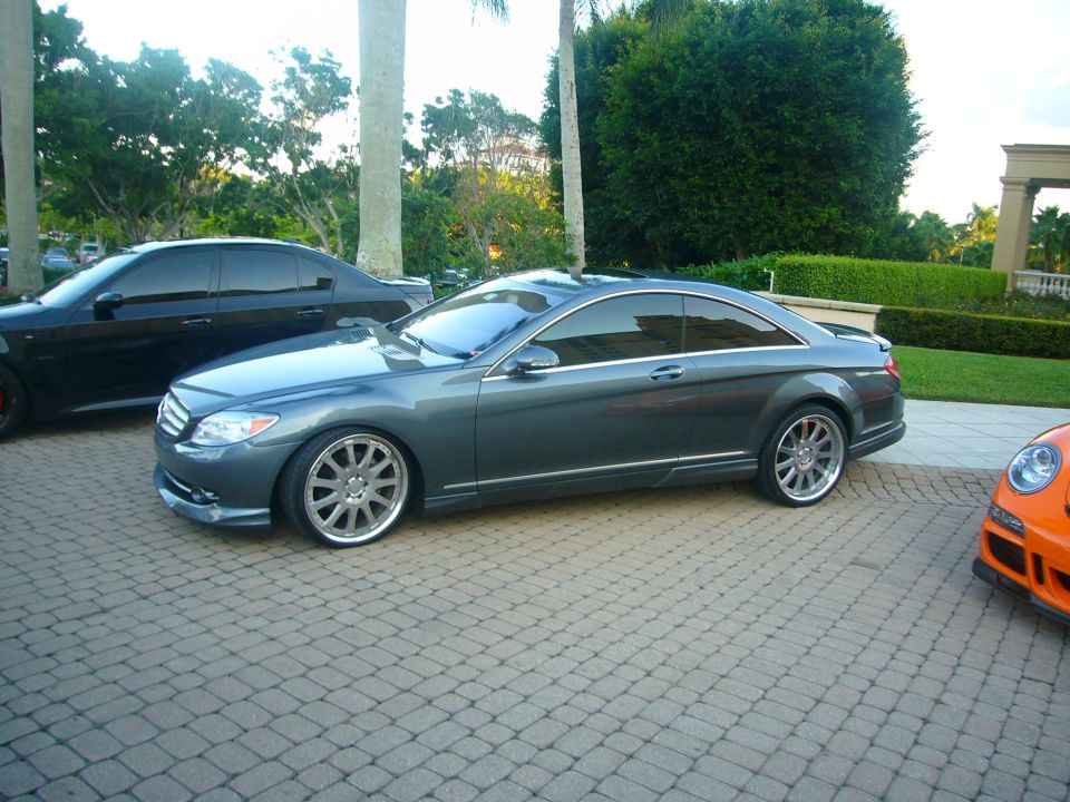 Gray Mercedes-Benz CL-Class coupe parked on a brick driveway next to a black sedan and an orange sports car