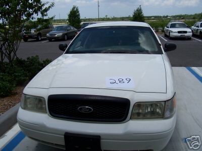 2001 Ford Crown Victoria - Front view of a white 2001 Ford Crown Victoria parked in a lot with other vehicles.
