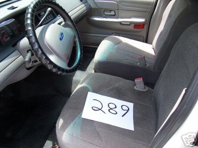 2001 Ford Crown Victoria - The interior of a 2001 Ford Crown Victoria is visible, the steering wheel, dashboard, and front seats with a paper labeled '289' placed on…