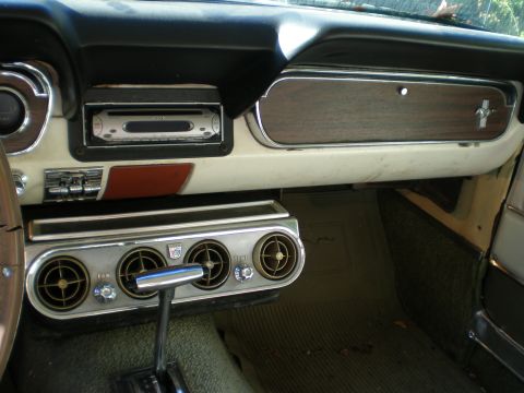 1966 Ford Mustang - The interior of a 1966 Ford Mustang shows its classic dashboard design with wood accents and functional air conditioning vents.