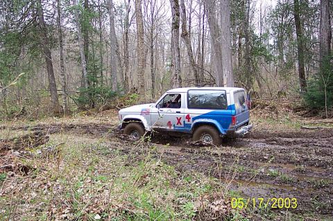1978 Ford Bronco - Ford Bronco II navigating a muddy trail in a wooded area.