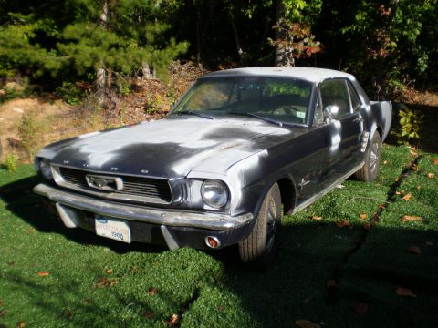 1966 Ford Mustang - A 1966 Ford Mustang coupe with a primer-covered hood sits on a grassy lawn.