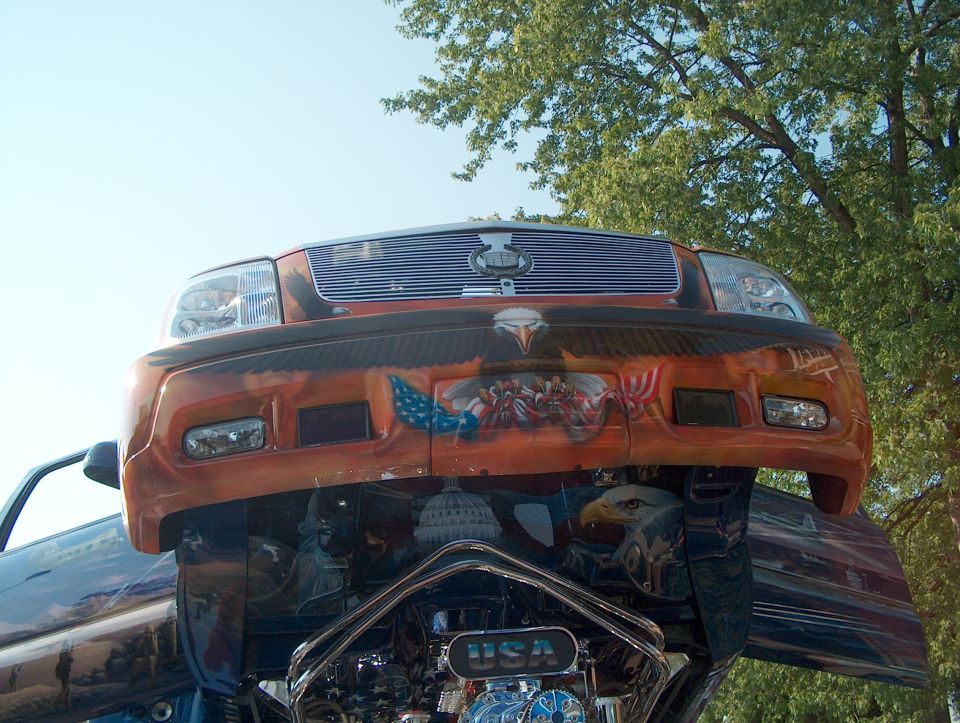 Orange SUV front end with eagle and flag airbrushing. Chrome grille and USA lettering visible