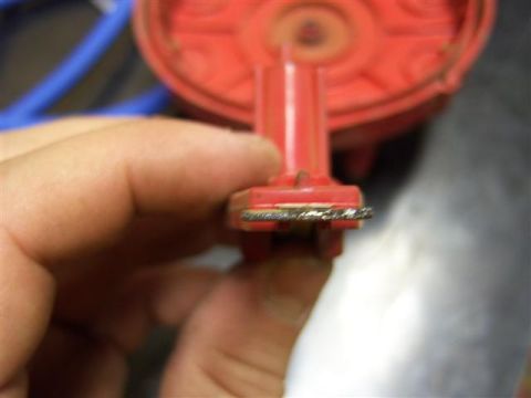 1995 Ford Bronco - Hand holding a red distributor rotor, showing wear on the edge.