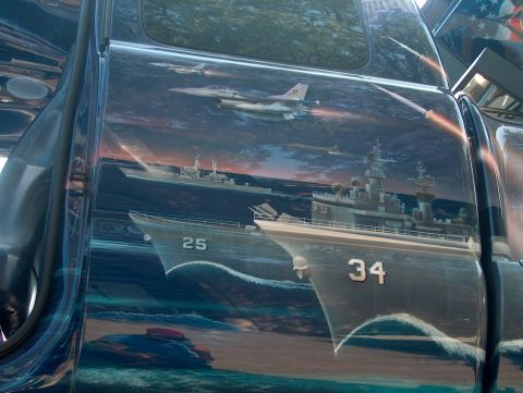 1978 Ford Bronco - A vehicle side features a detailed mural depicting jets engaged in combat with battleships at sea.
