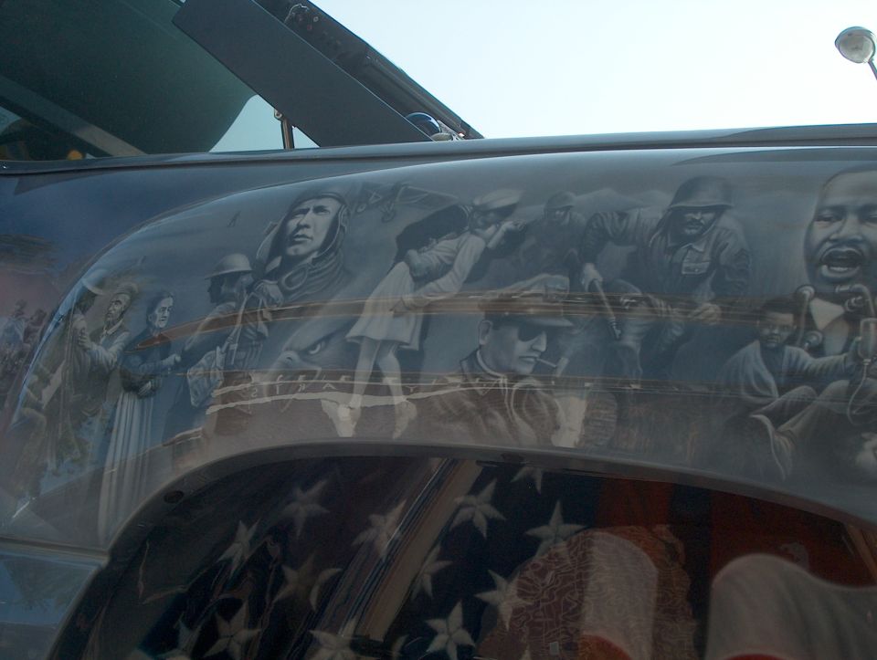Airbrushed grayscale mural of soldiers and historical figures on a vehicle body side