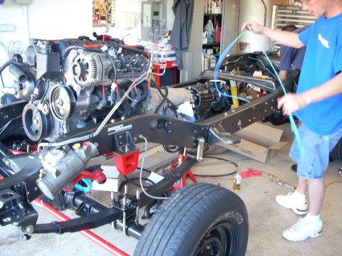 1992 Ford Bronco - A person works on the wiring of a vehicle's chassis and engine assembly in a garage setting.