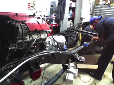 1992 Ford Bronco - Mechanics work on an engine and chassis assembly, possibly for a custom build or repair.