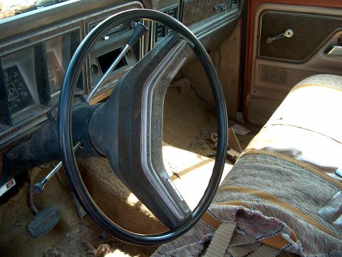 1979 Ford F-250 - The interior of a 1979 Ford F-250 shows wear and tear, with a patterned seat cover and a cracked dashboard.