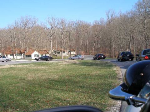 2001 Ford Crown Victoria - A collection of vehicles are visible on a road, with buildings and a wooded area behind them.